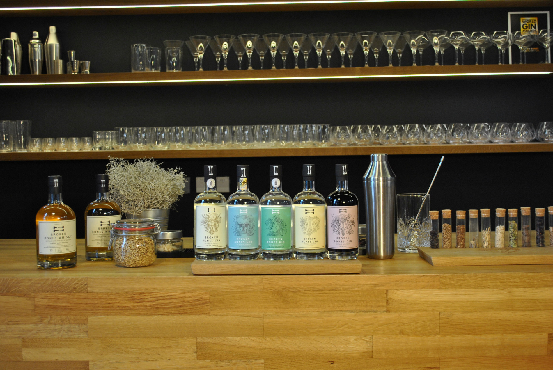 Five bottles on a wooden base. Glass jars in the background.
