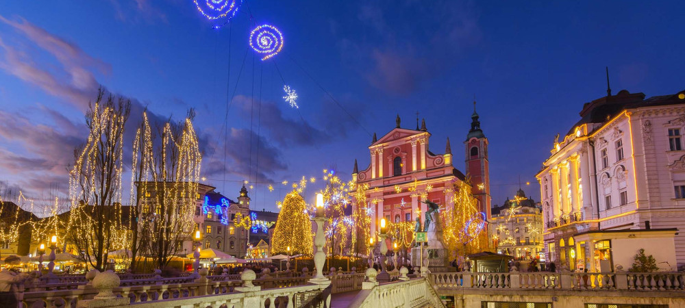 Praznično razsvetljen Tromostovje. V ozadju Prešernov trg.