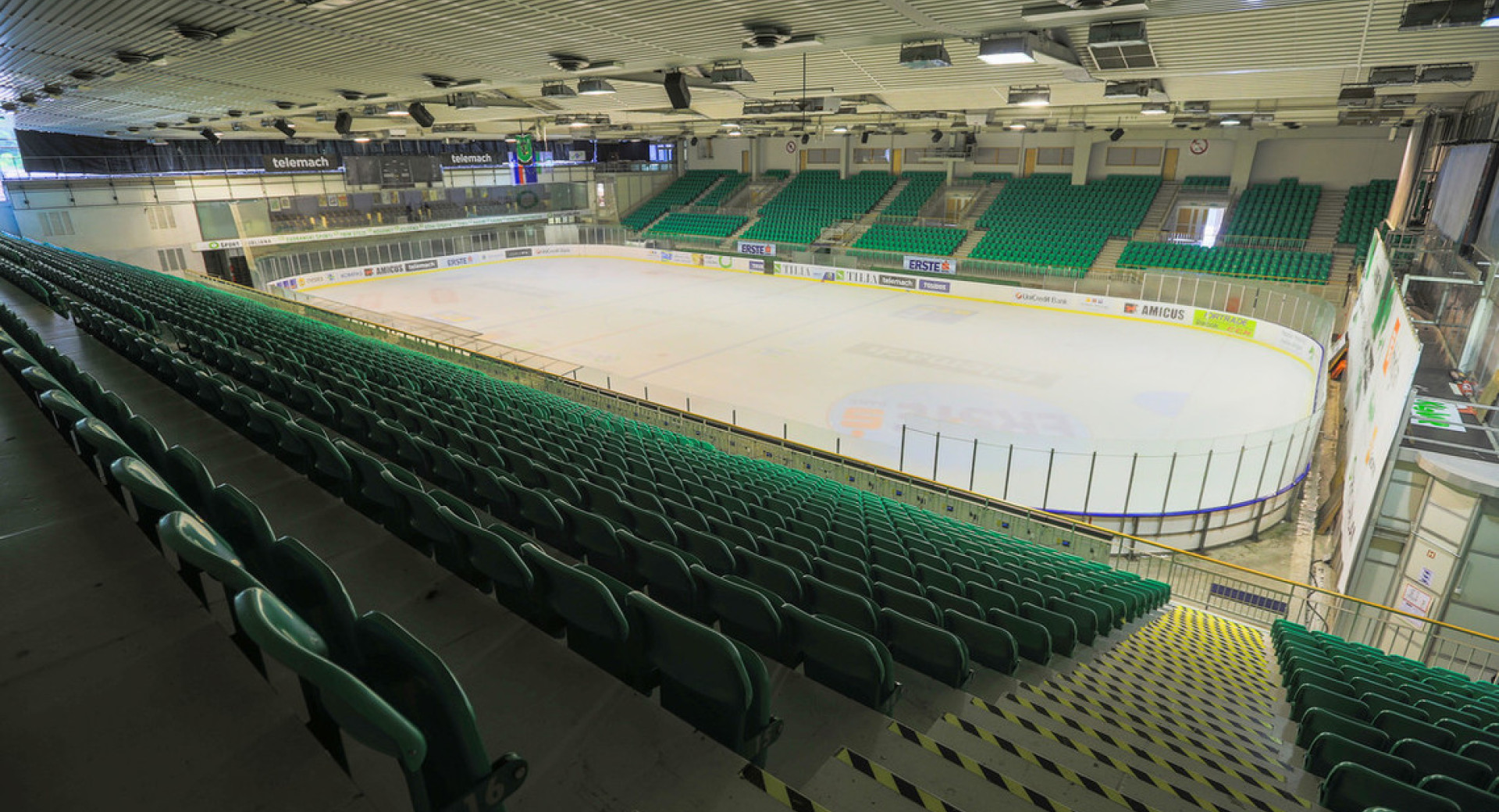 A big sports hall with green grandstand.