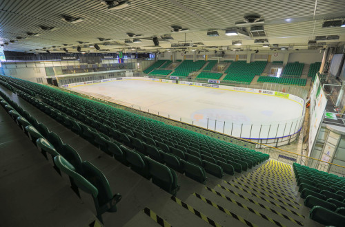 A big sports hall with green grandstand.