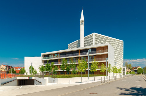 A large white building made of steel and exposed wood. Minaret in the middle.