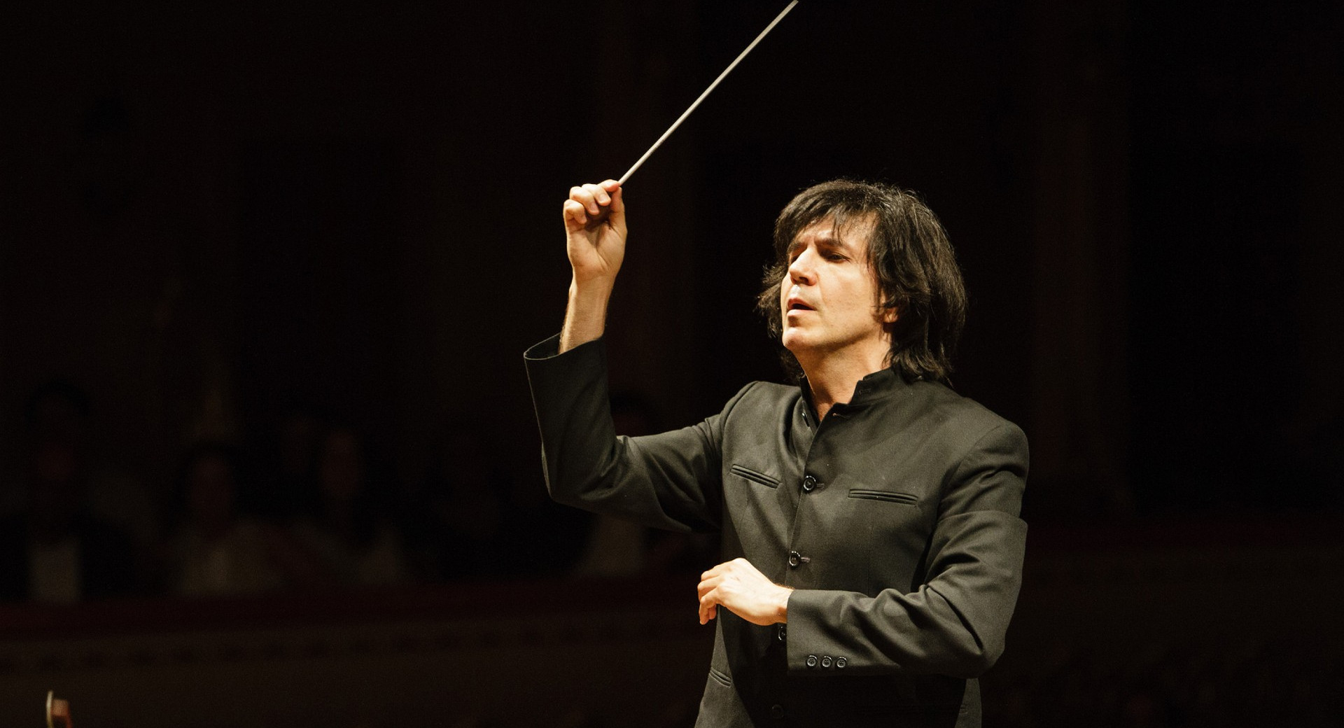 Dirigent v črnem suknjiču na koncertu.