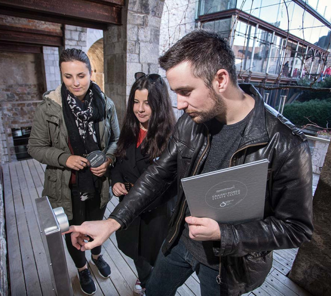 Trije udelezenci Grajskega pobega resujejo uganke.