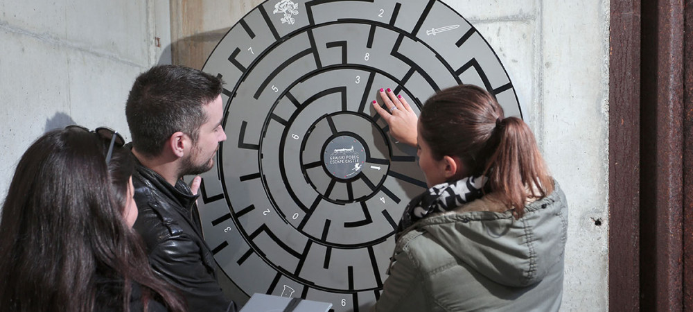 Trije obiskovalci ob resevanju uganke.