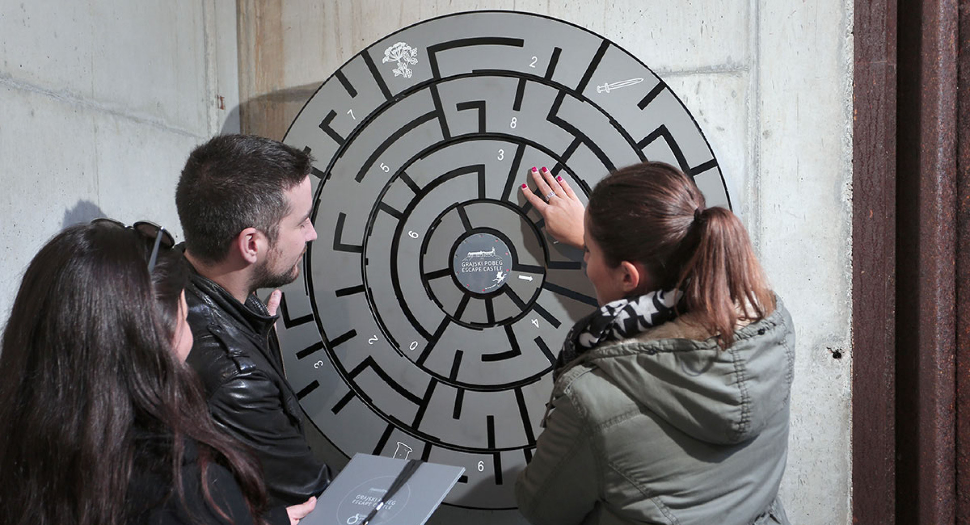 Trije obiskovalci ob resevanju uganke.