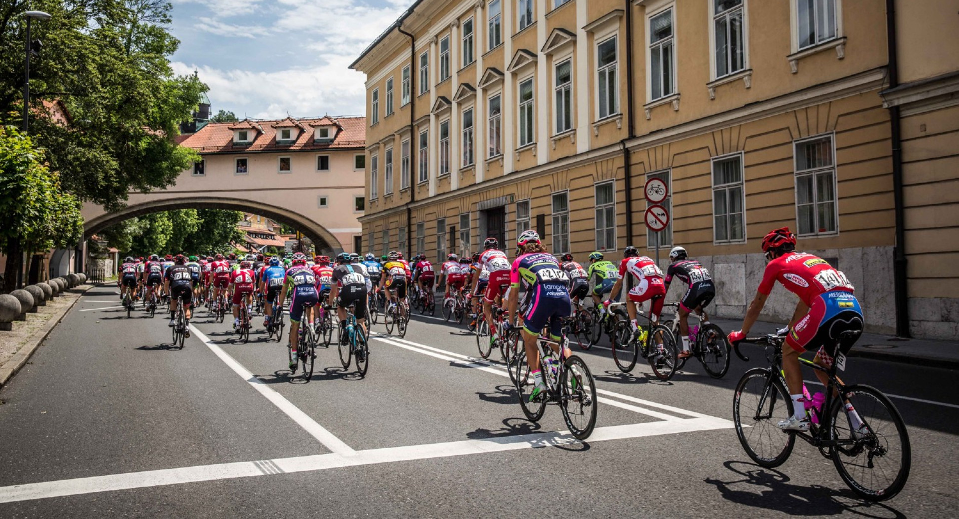 Cyclists in colourful jerseys are riding on a road in the city.