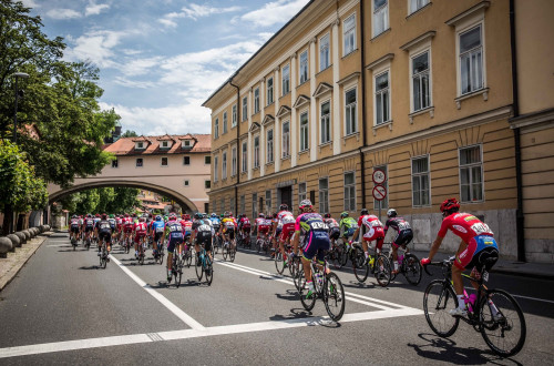 Cyclists in colourful jerseys are riding on a road in the city.