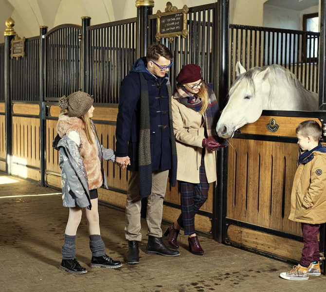 Una famiglia in una stalla accanto a un cavallo bianco.