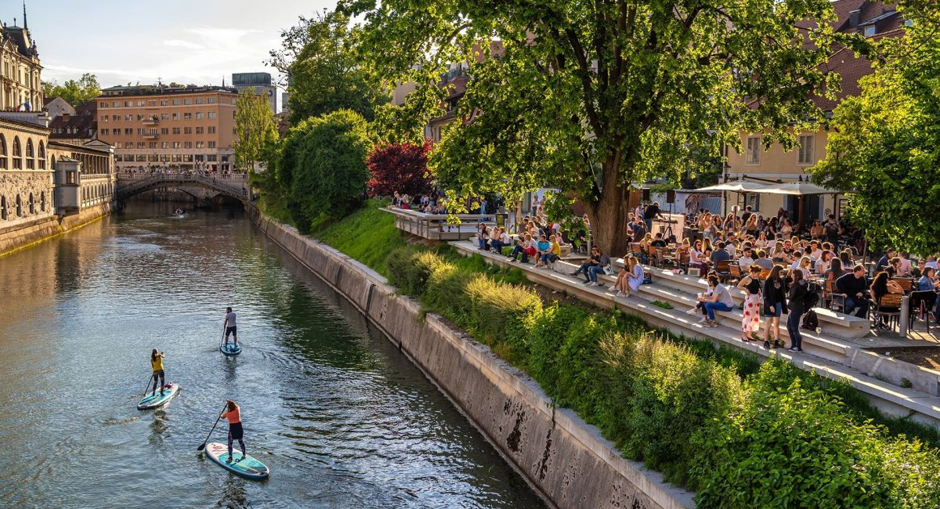 Supanje skozi Ljubljano, na desni strani ljudje na Petkovškovem nabrežju.