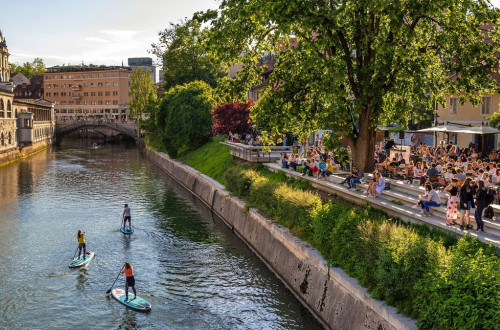 Supanje skozi Ljubljano, na desni strani ljudje na Petkovškovem nabrežju.