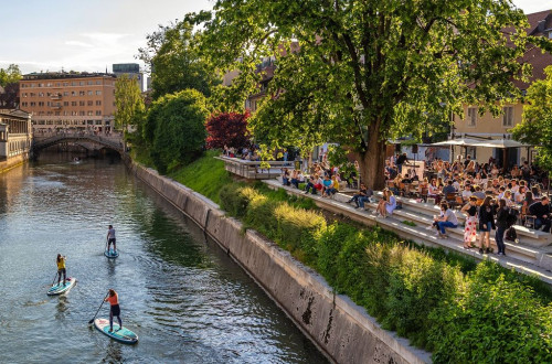 Supanje skozi Ljubljano, na desni strani ljudje na Petkovškovem nabrežju.