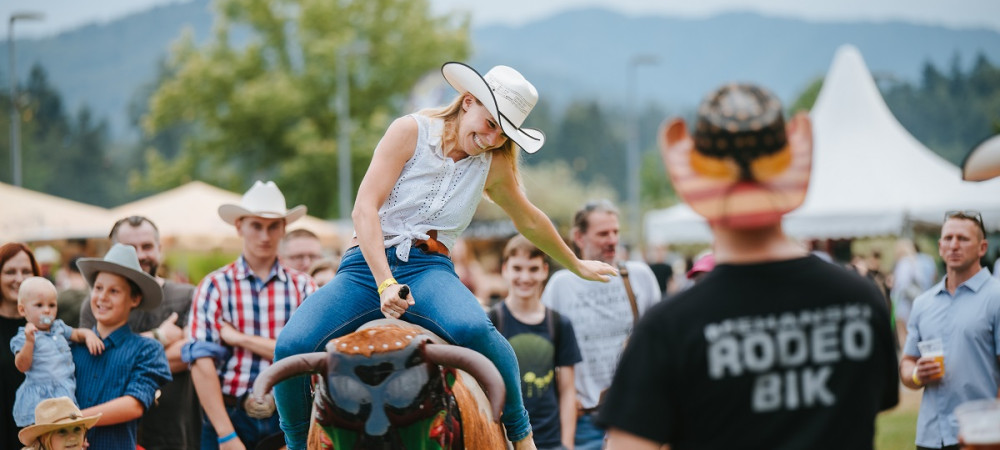 A woman riding a bull. A group of people in the background.