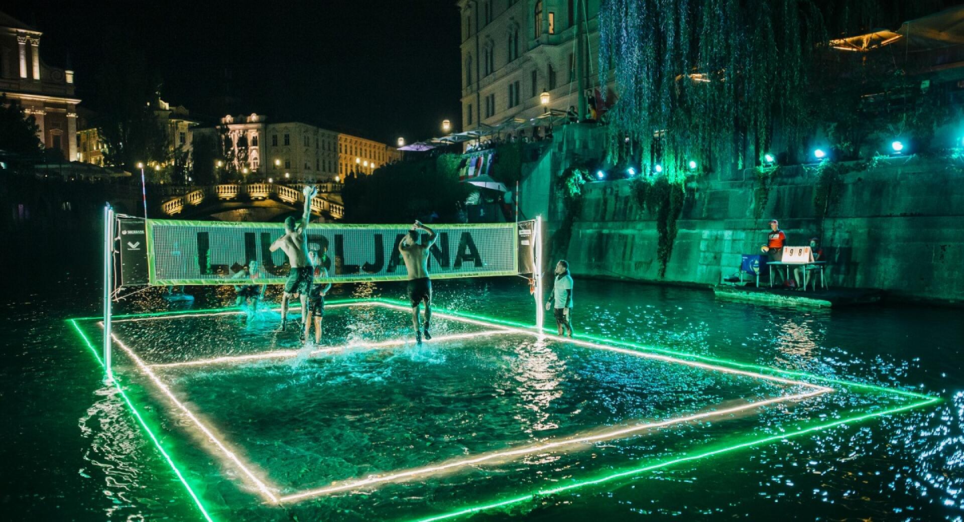 Odbojkasko igrisce na vodni gladini. Noc, igrisce osvetljeno z lucmi.