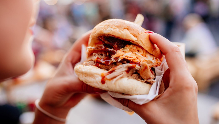 Hands holding a coated hamburger,