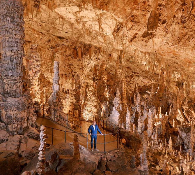 Un visiteur dans la grotte avec de nombreuses stalagmites et stalactites.
