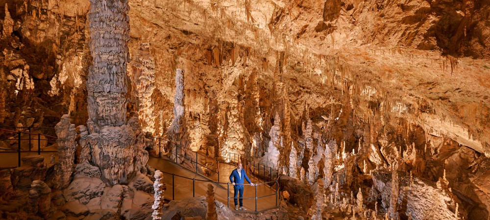 A person inside a cave with a lot of  stalactites.