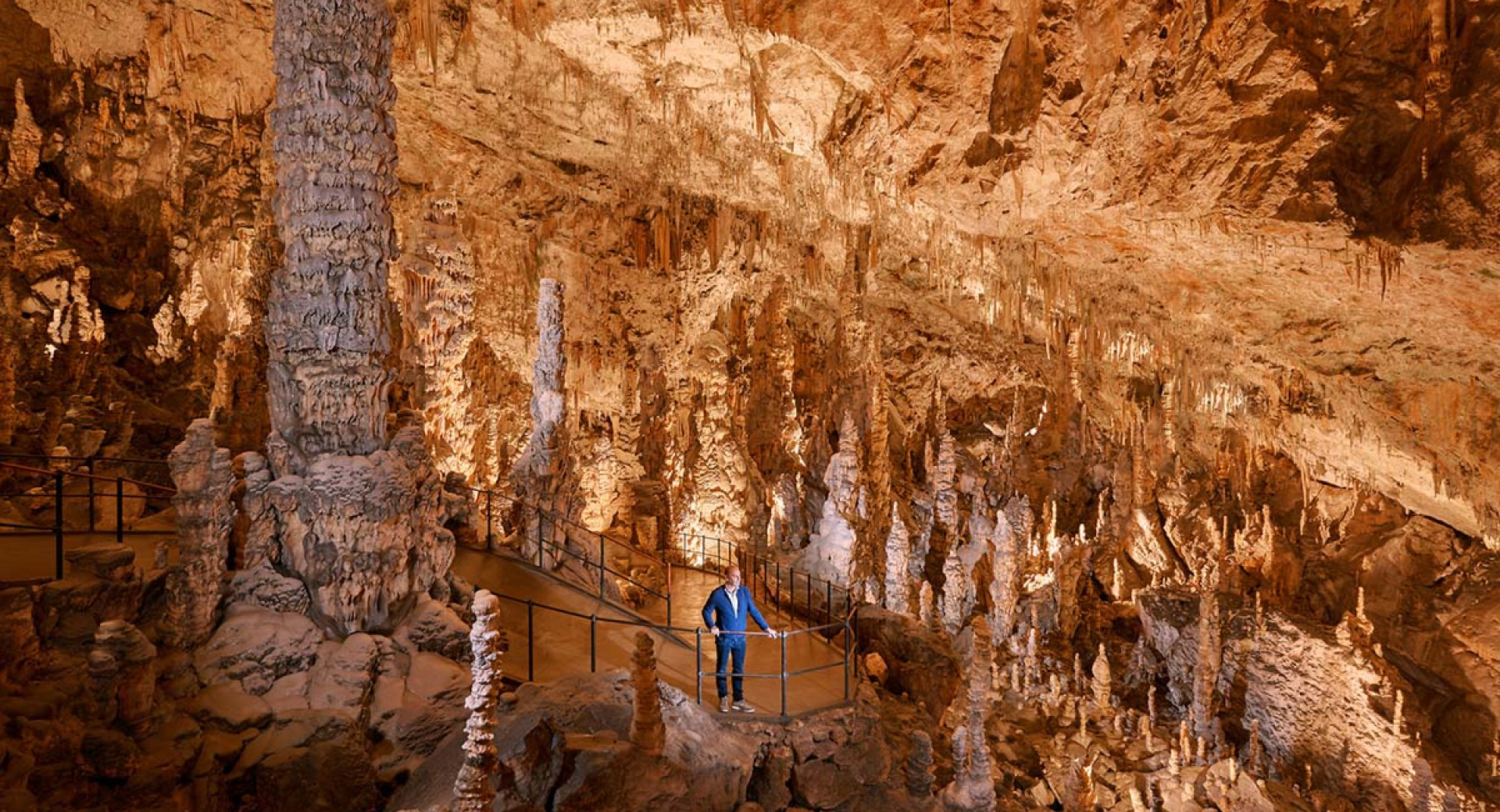Un visitatore in una grotta con molte stalattiti.