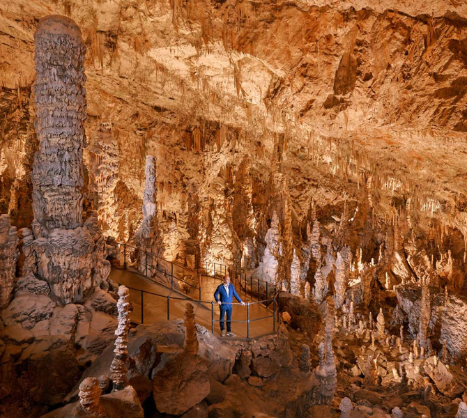 Un visitatore in una grotta con molte stalattiti.