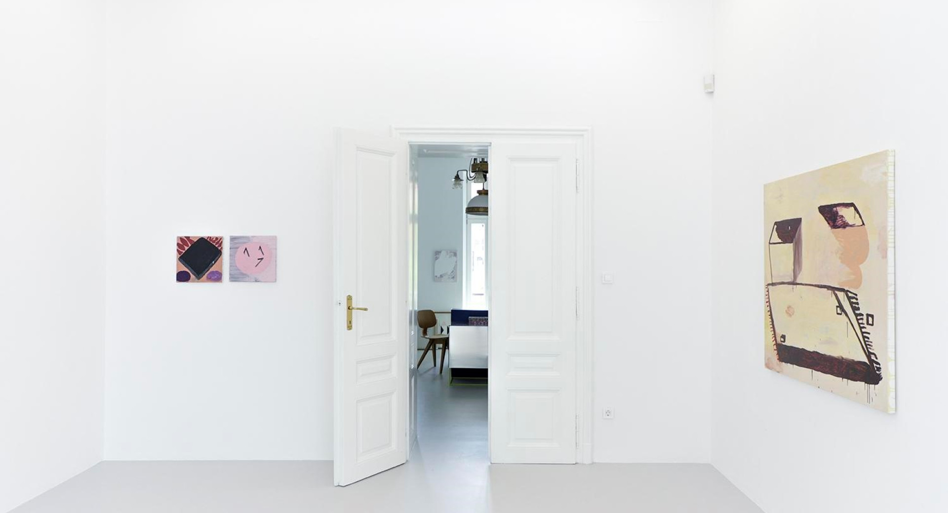 Bela soba z odprtimi vrati in dvema slikama na steni.