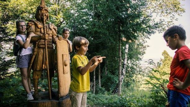 Otroci ob lesenem kipu rimskega vojaka.