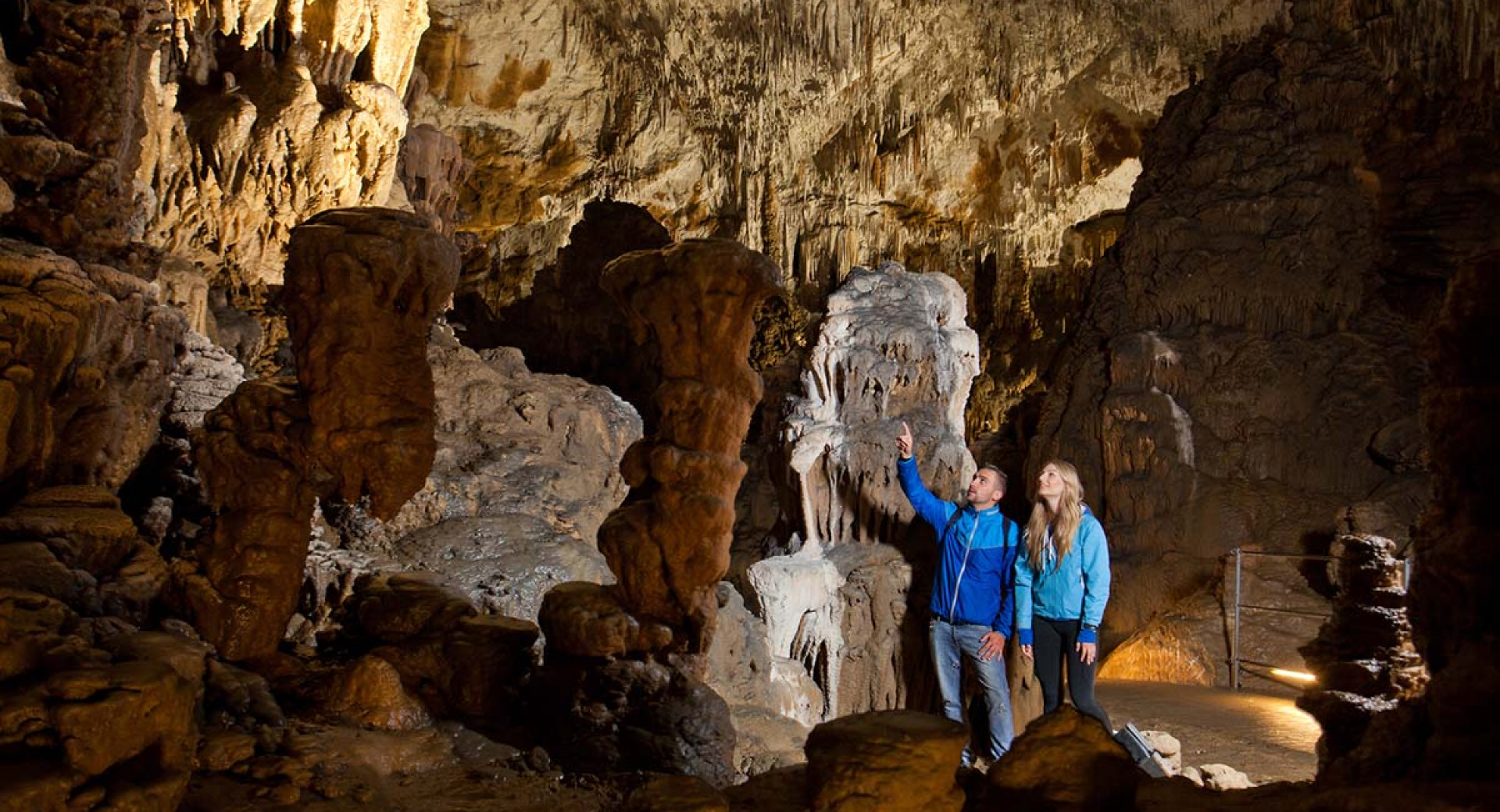 The visitors in the cave admire the stalactites and stalagmites.