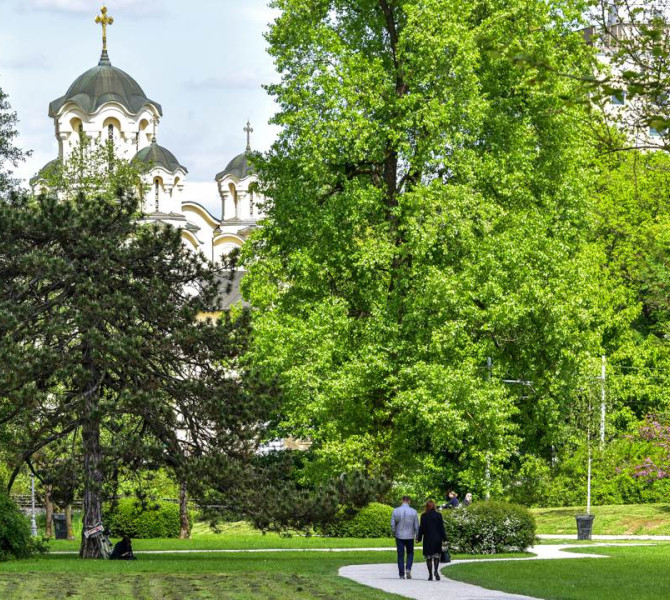 Ein Park mit Bäumen, im Hintergrund eine protestantische Kirche.