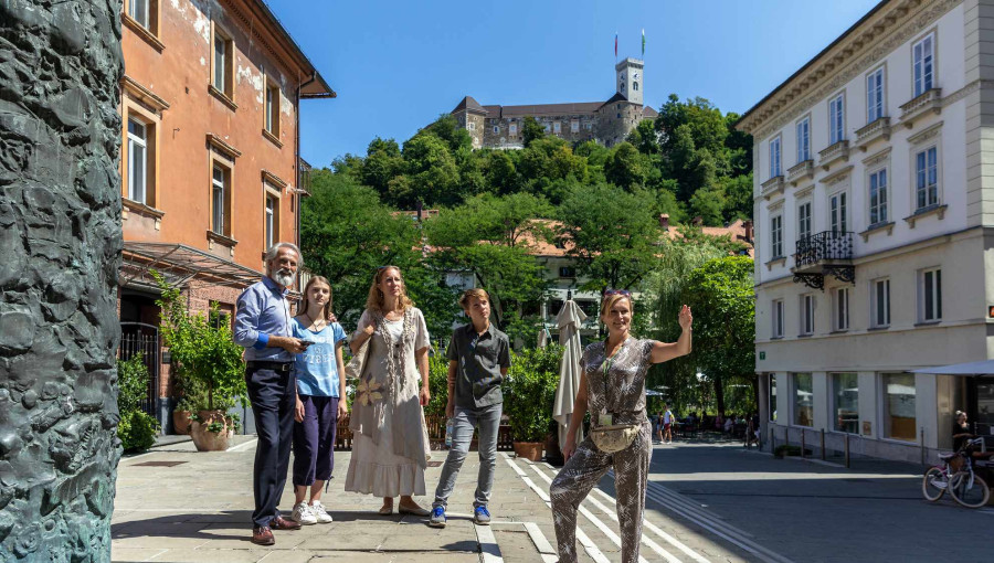 Druzina na turisticnem vodenju po Ljubljani, v ozadju Ljubljanski grad.