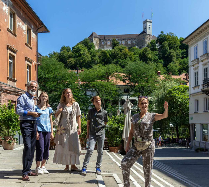 Turistično vodenje po Ljubljani v ozadju Ljubljanski grad.