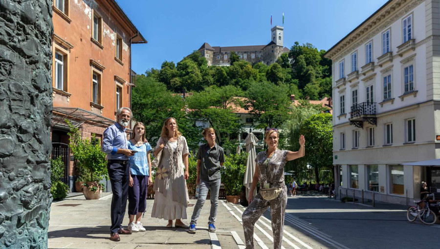 Turistično vodenje po Ljubljani v ozadju Ljubljanski grad.