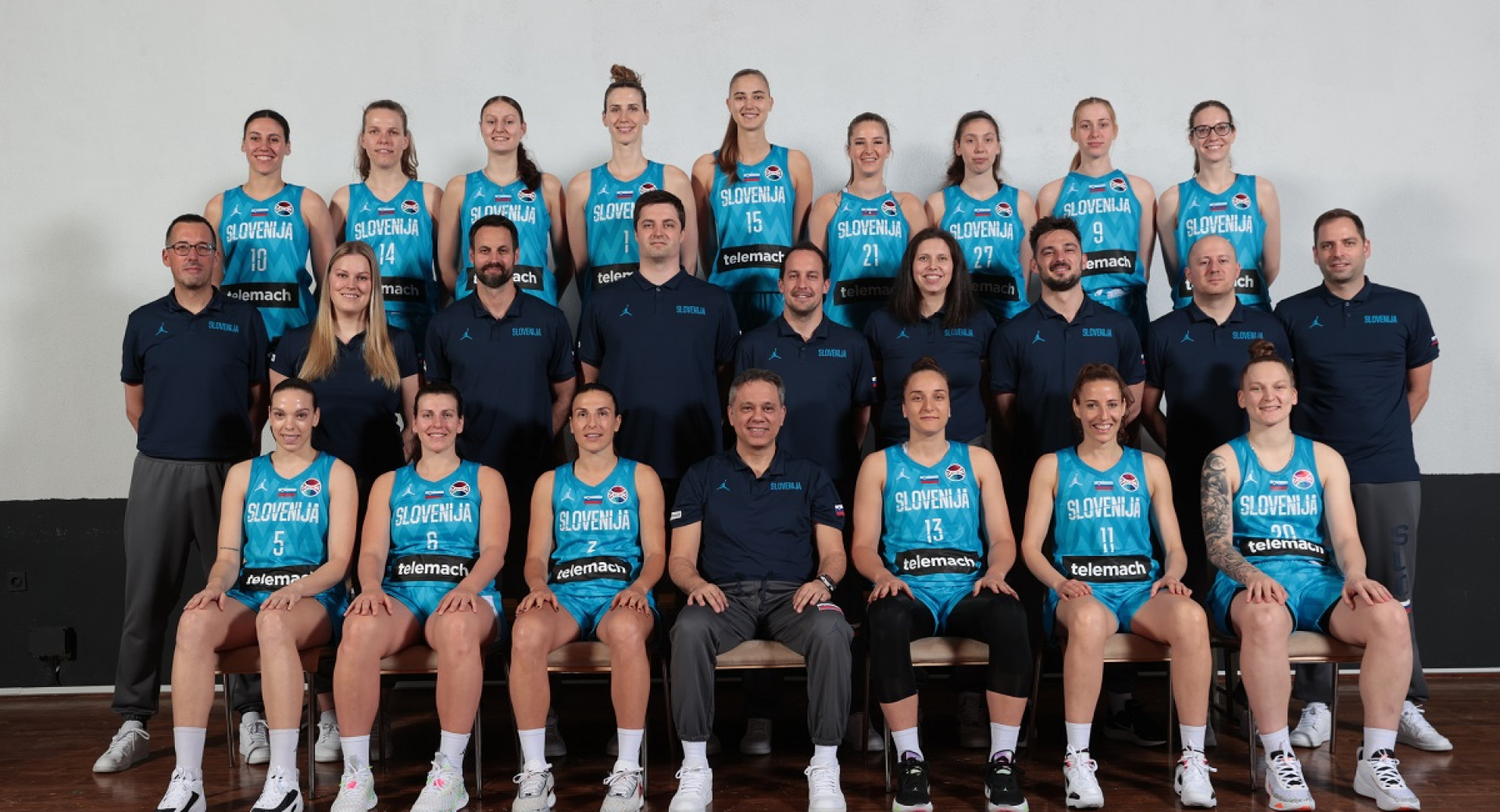 Three rows of female basketball players in blue sports uniforms.