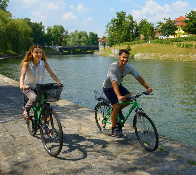 Dva kolesarja ob reki Ljubljanici v Ljubljani.