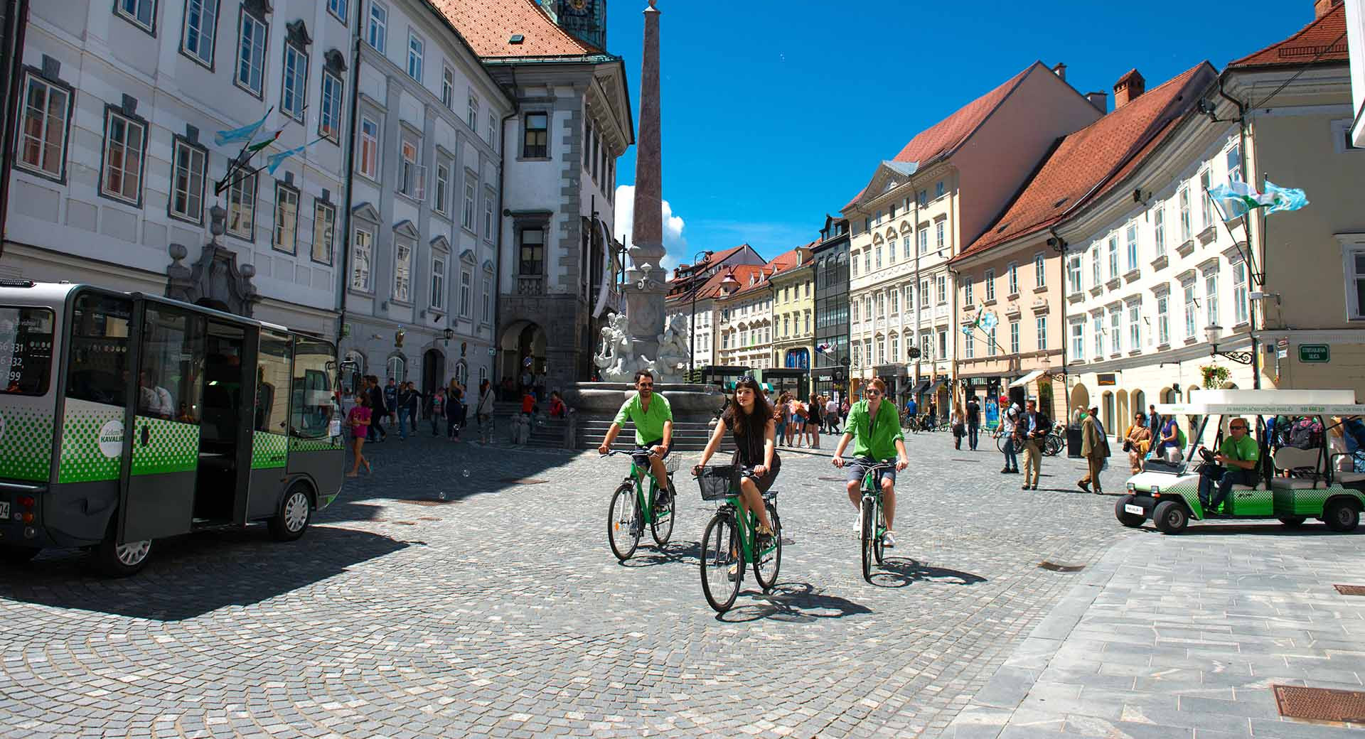 Trije kolesarji na Mestnem trgu v Ljubljani.