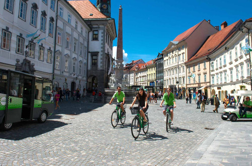 Trije kolesarji na Mestnem trgu v Ljubljani.