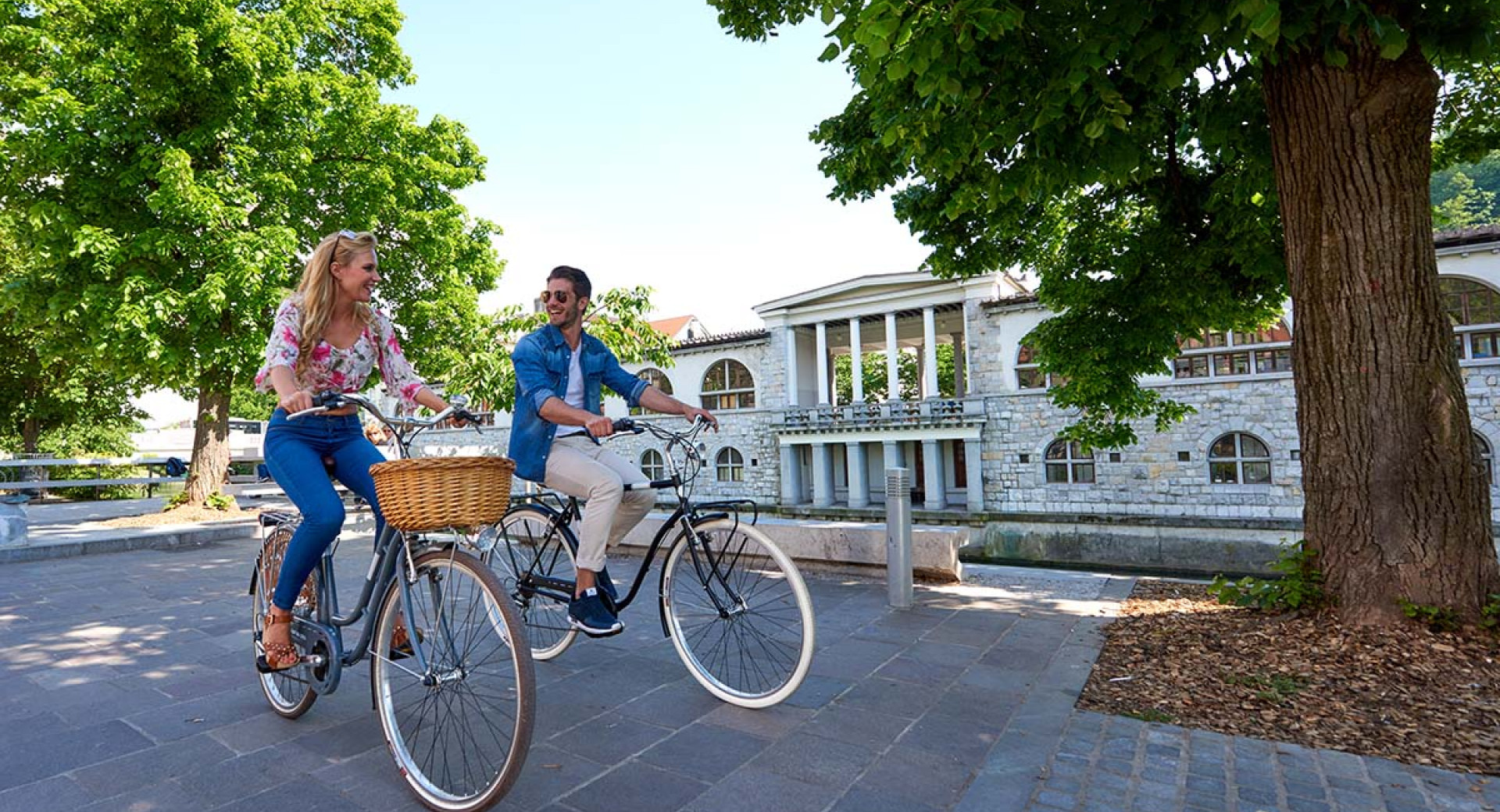 Kolesarja ob Ljubljanici. Za njima Plečnikova glavna tržnica.