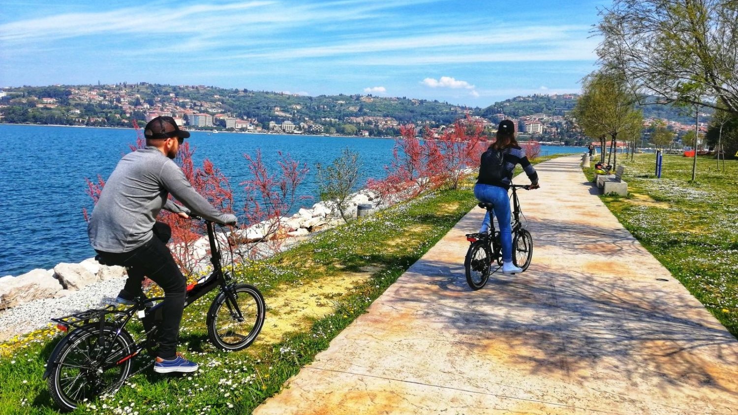 Kolesarja ob morju v Kopru. V ozadju polotok.