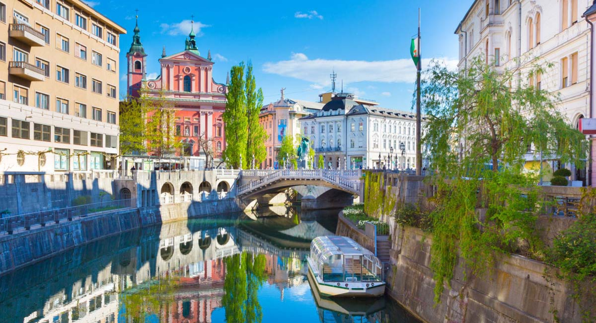 Razgled iz mostu na turistično ladjo na Ljubljanici. V ozadju Tromostovje in Prešernov trg.