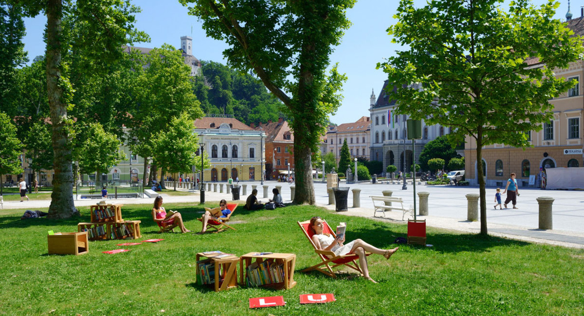 dekleta na ležalniku v Parku zvezda berejo knjige v okviru Knjižnice pod krošnjami.