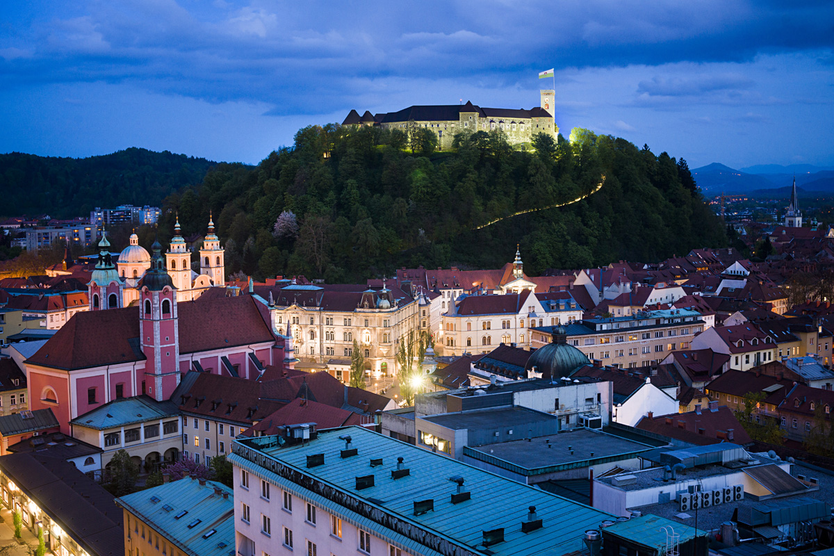 Nočna panorama Ljubljane z Ljubljanskim gradom v ozadju.