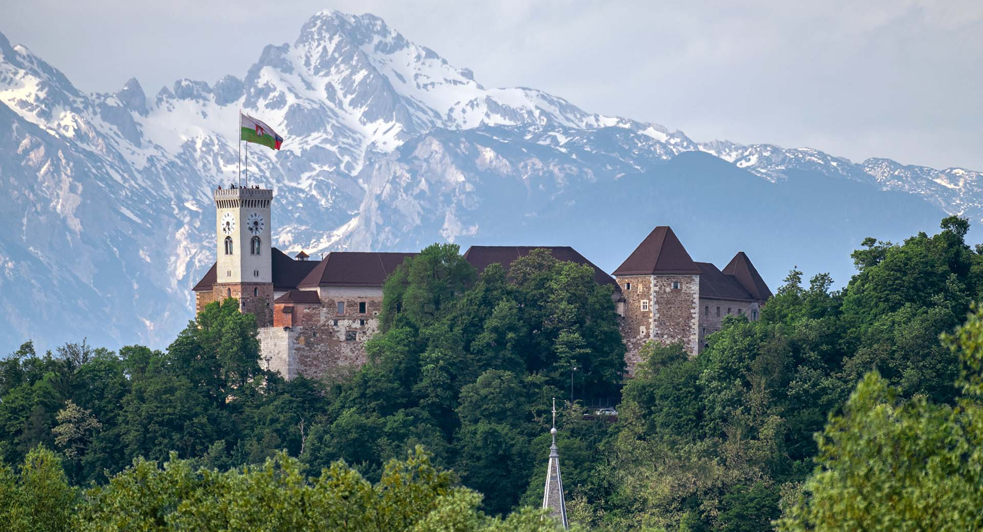 Ljubljanski grad na grajskem gricu. V ozadju zasnezene gore.