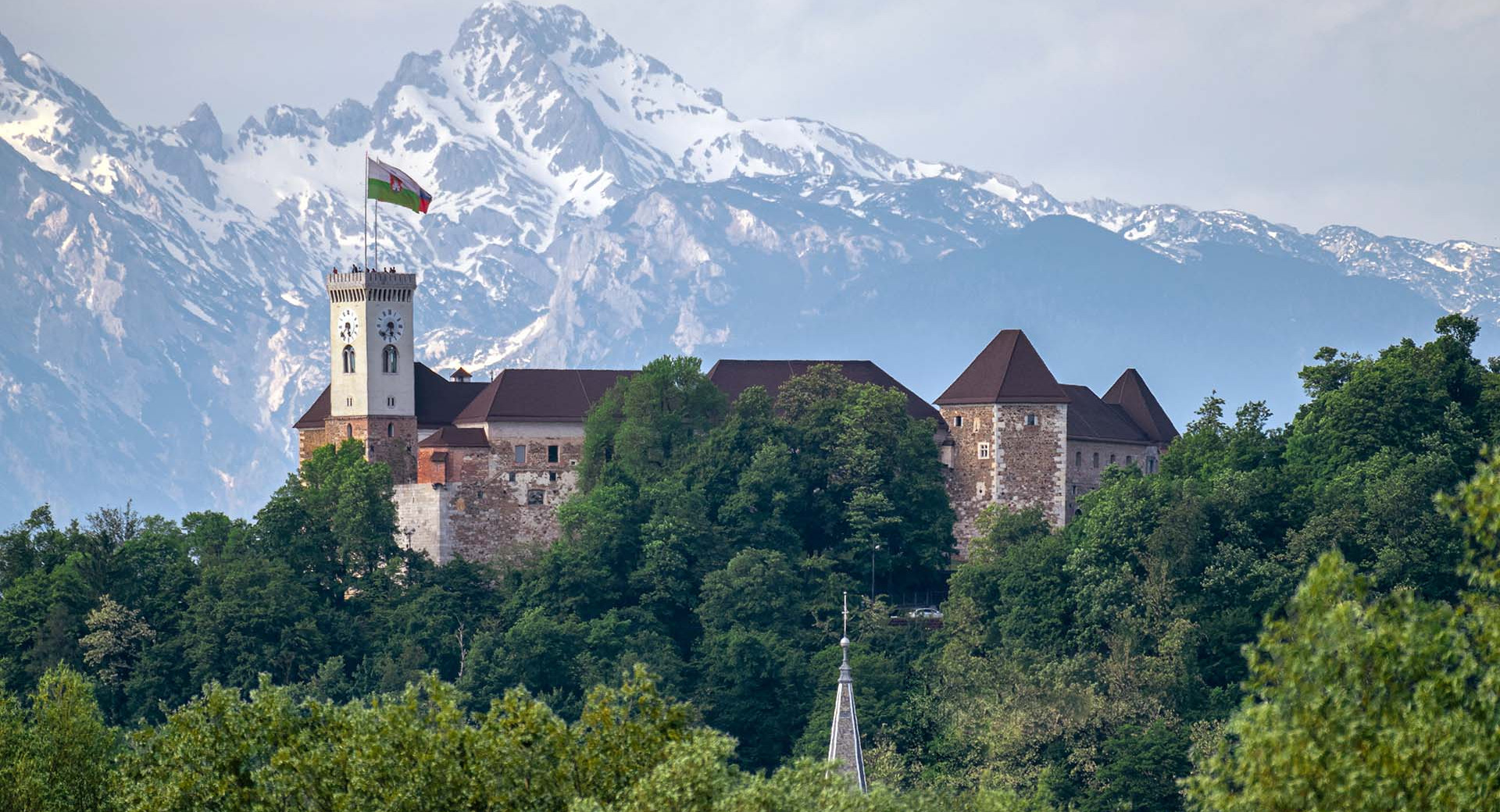 Ljubljanski grad na grajskem hribu. V ozadju zasnežene gore.