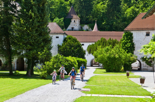 Družina kolesari pred gradom Bistra.