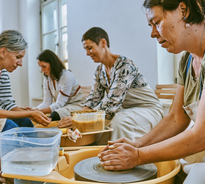 Les participantes modelent l’argile lors d’un atelier de poterie, créant ensemble sur des roues tournantes.