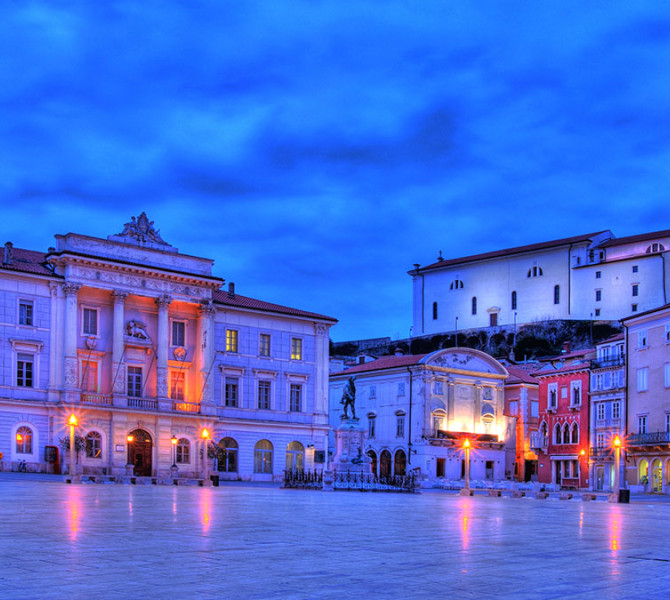 A spacious stone square surrounded by historic architecture at dusk.