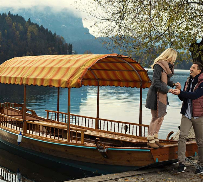 Una barca sul lago, una ragazza scende, un ragazzo le tiene la mano.