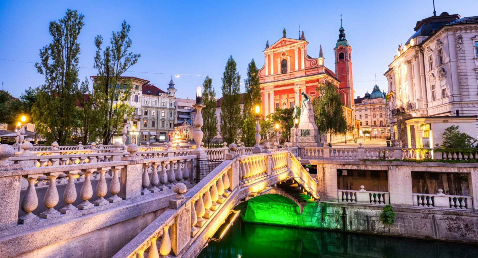 Tromostovje in Prešernov trg s Frančiškansko cerkvijo zvečer.