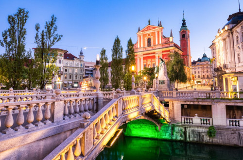 Tromostovje in Prešernov trg s Frančiškansko cerkvijo zvečer.