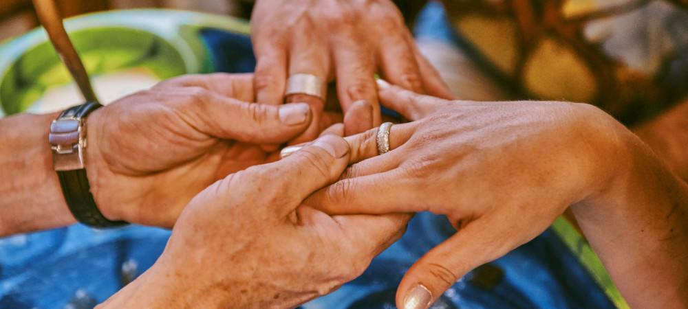 Rings on a women's and man's hand, held by a goldsmith.