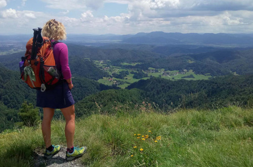 Pohodnica občuduje razgled na dolino in okoliške hribe.