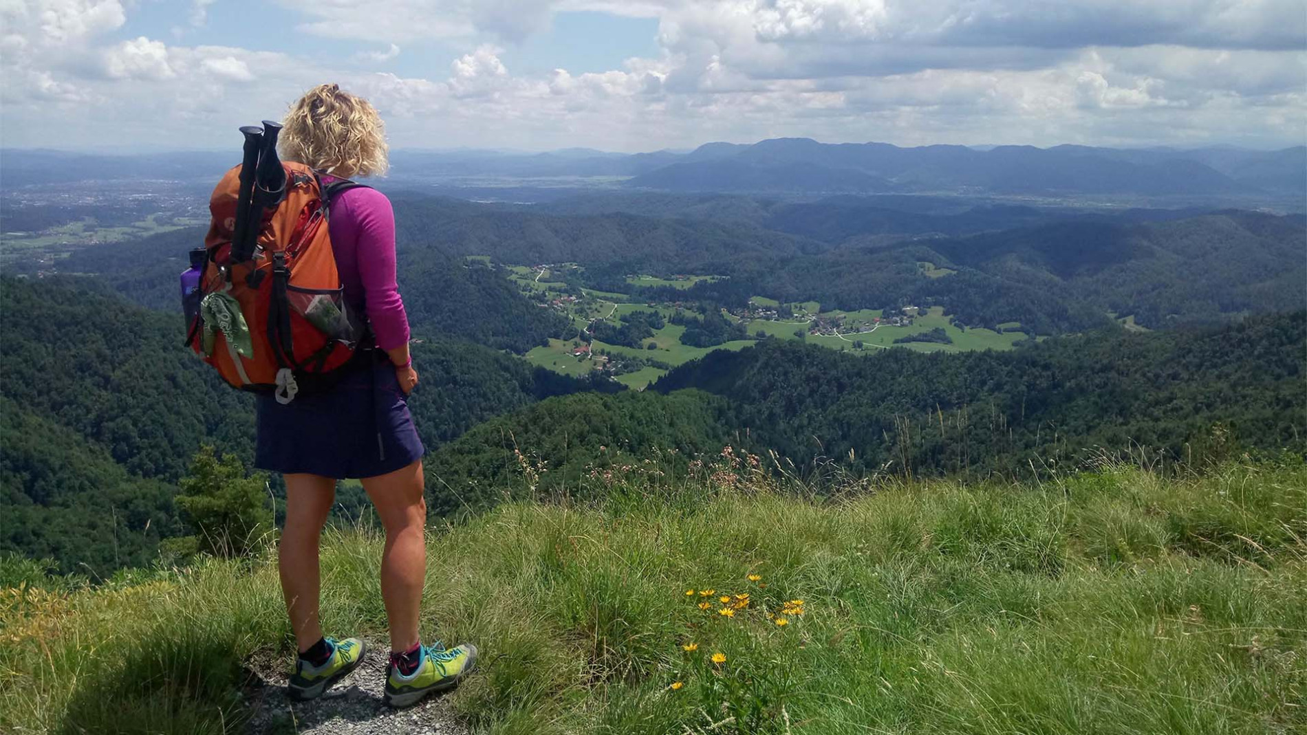 Pohodnica občuduje razgled na dolino in okoliške hribe.