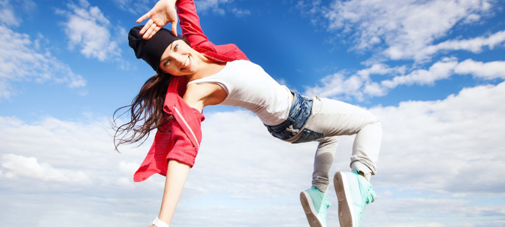 female breakdance dancer in a dance pose, with a blue sky in the background